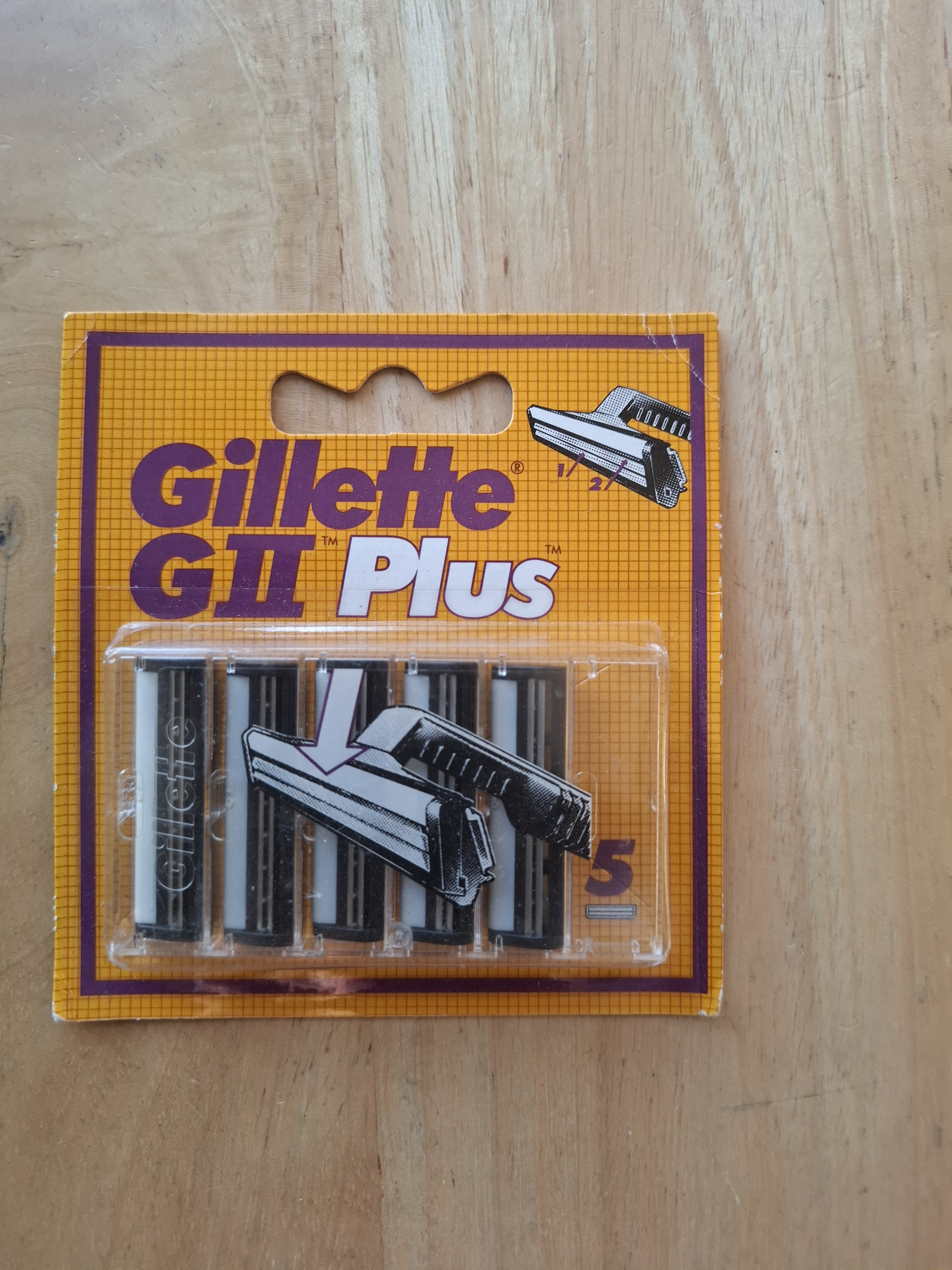 Gillette GII Plus card front, showing mustard-yellow grid livery, purple downward-arrow graphic and five-cartridge tray